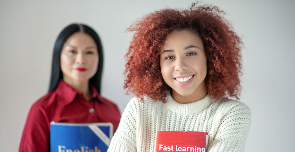 Universidad DARUMA, Inicio, Una maestra y una estudiante ambas cargando un libro de ingles cada una,